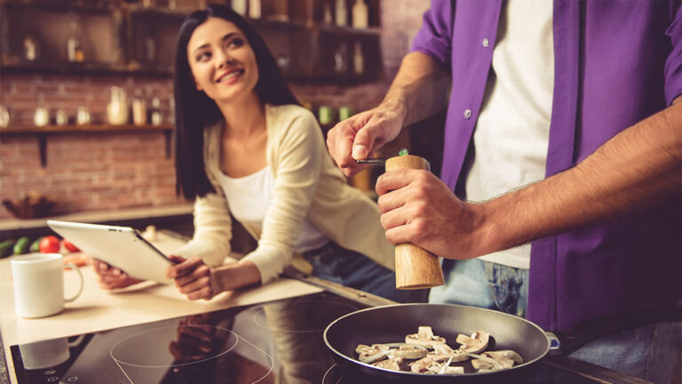 Casal cozinhando em casa em cooktop