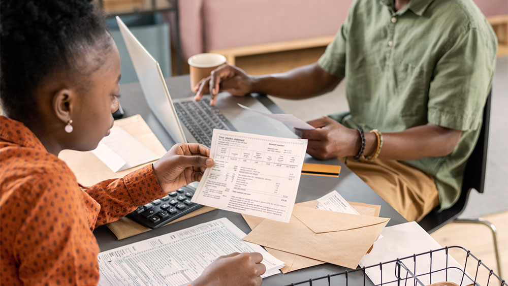Casal analisando contas de energia e boletos em casa, representando a TUSD e os custos de distribuição na conta de luz.